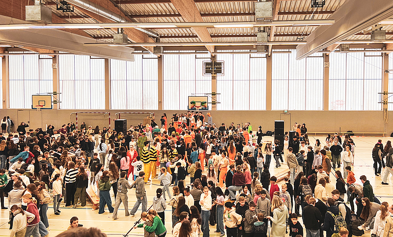 Das Foto zeigt den innenraum der Sporthalle mit den feiernden Schüler:innen 
