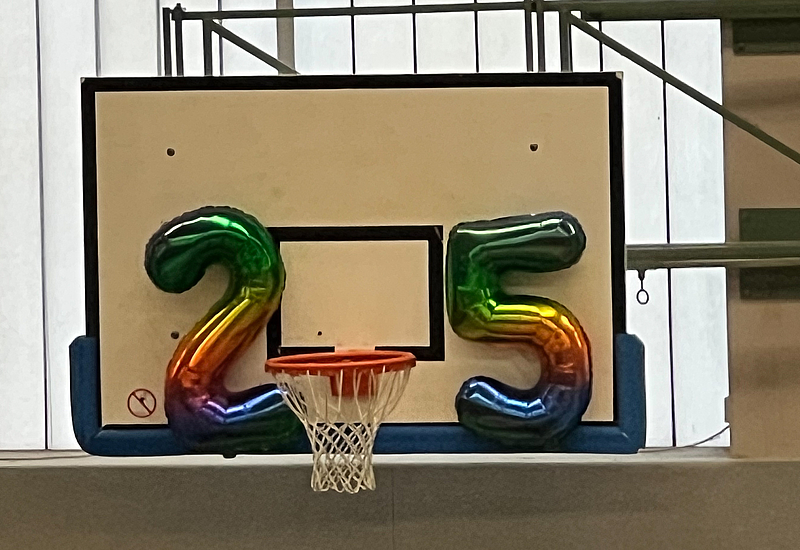 Das Foto zeigt einen Baskettballkorb mit zwei Luftballons in Form der 25